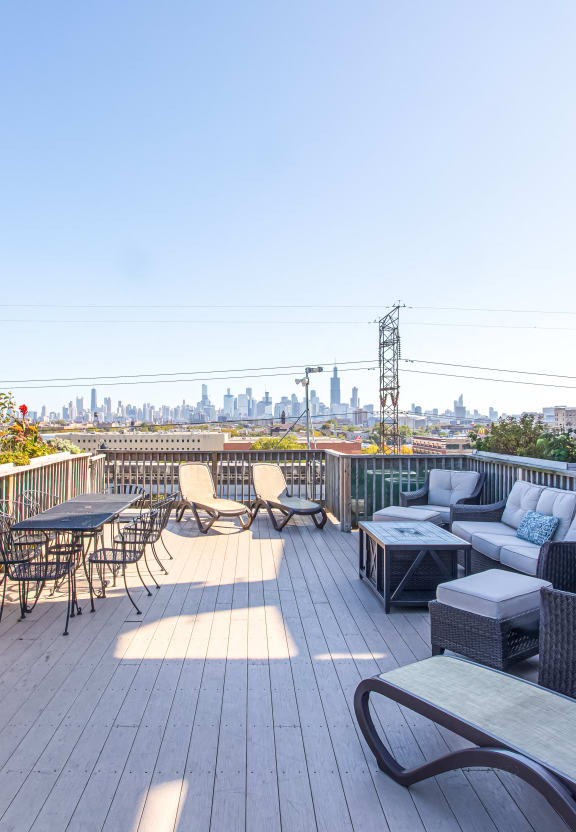 a rooftop deck with furniture and a city in the background
