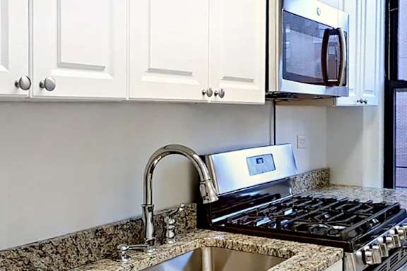 A kitchen with white cabinets and granite countertops.at Sutton Collection, New York