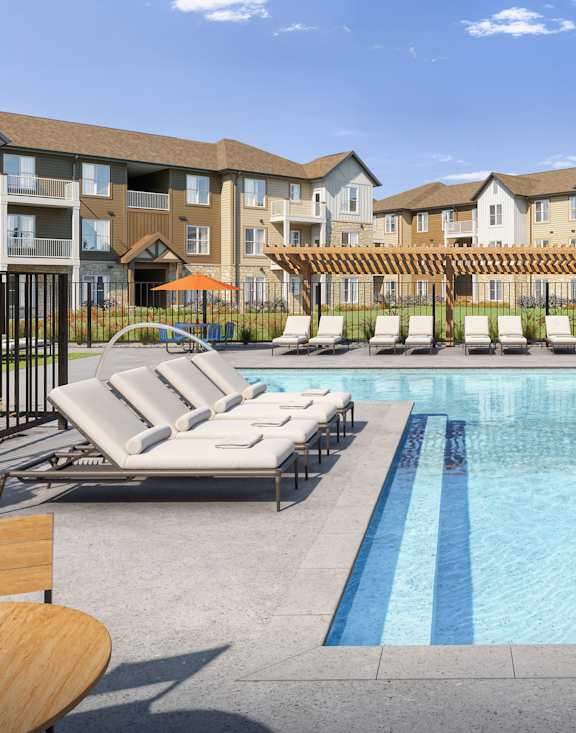 A pool surrounded by lounge chairs and trees.