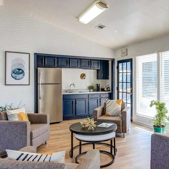 A modern living room with a grey sofa, a coffee table, and a kitchen in the background.