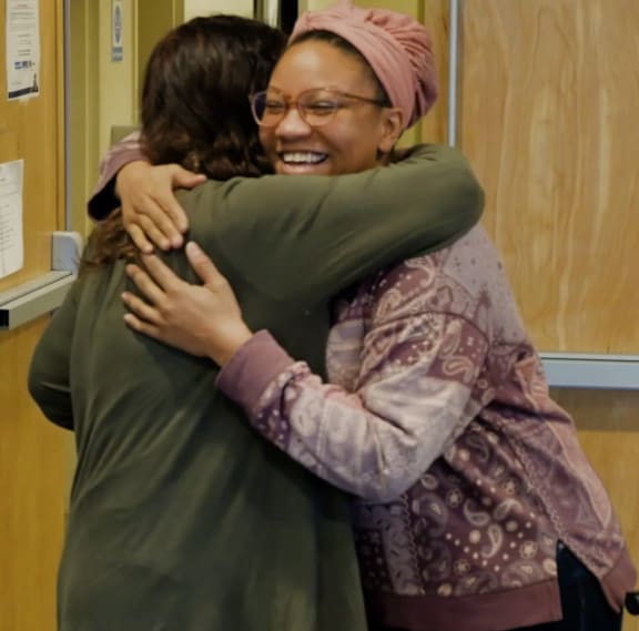 Two people hug each other in a room.