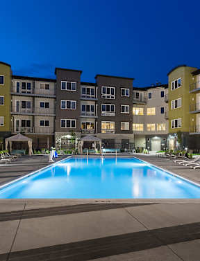A swimming pool surrounded by apartment buildings at dusk.