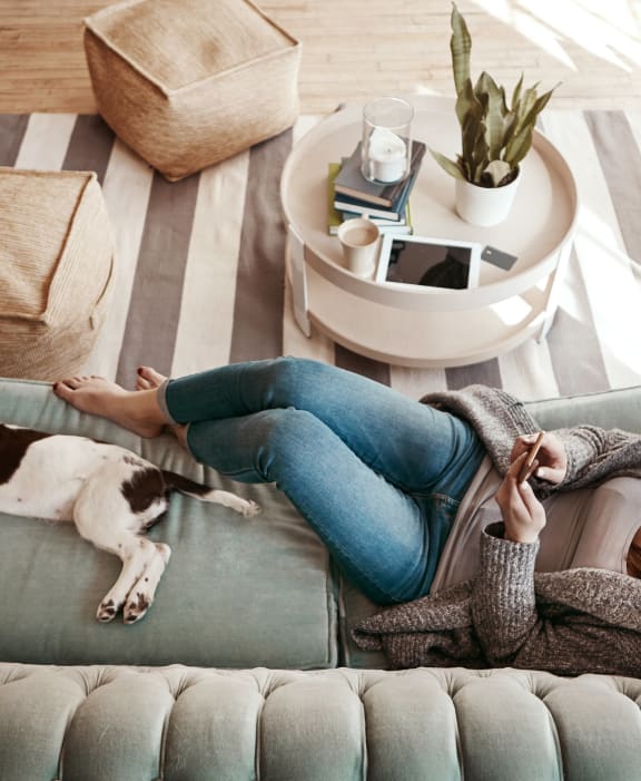 Woman Lounging on Couch with Dog at Cedartree Apartments in Santa Clara, CA