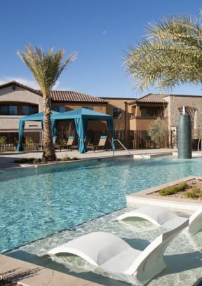 a swimming pool with chaise lounge chairs and umbrellas in front of a hotel