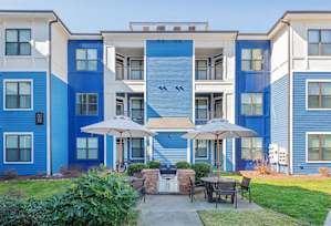a patio with chairs and tables and a pool in the background at Streets of Greenbrier in Chesapeake, VA 23320