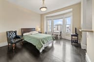 a bedroom with a bed and a chair and a window