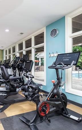 A gym with a row of stationary bikes and a television mounted on the wall.