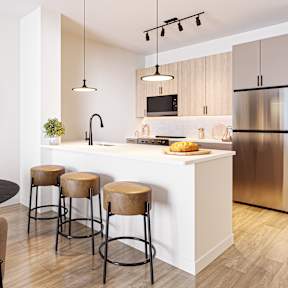 A modern kitchen with a round table and bar stools.