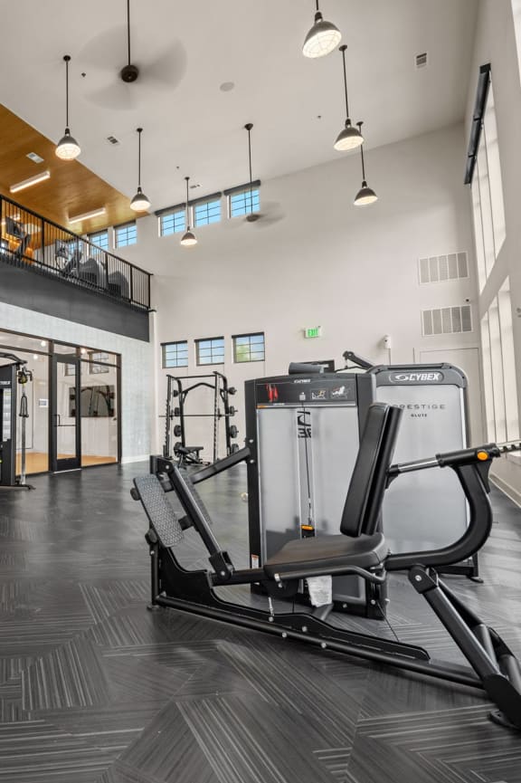 a gym with cardio equipment and weights in a building with tall windows