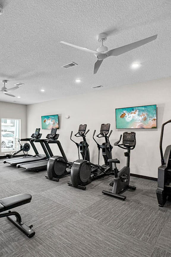 A spacious gym with a variety of equipment including treadmills, stationary bikes, and weight machines. at Sagebrook Apartments, La Vista, Nebraska