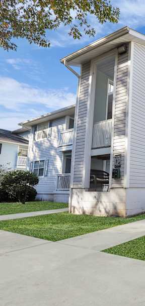 a white apartment building with stairs and a sidewalk
