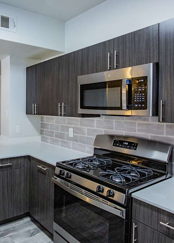 A modern kitchen with dark wood cabinets and a stainless steel oven.
