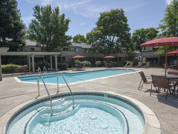 Sierra Glen apartments spa and pool area with lounge chairs, tables and sun umbrellas 