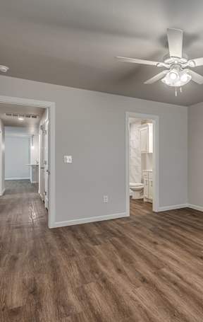 A room with a ceiling fan and wooden flooring.
