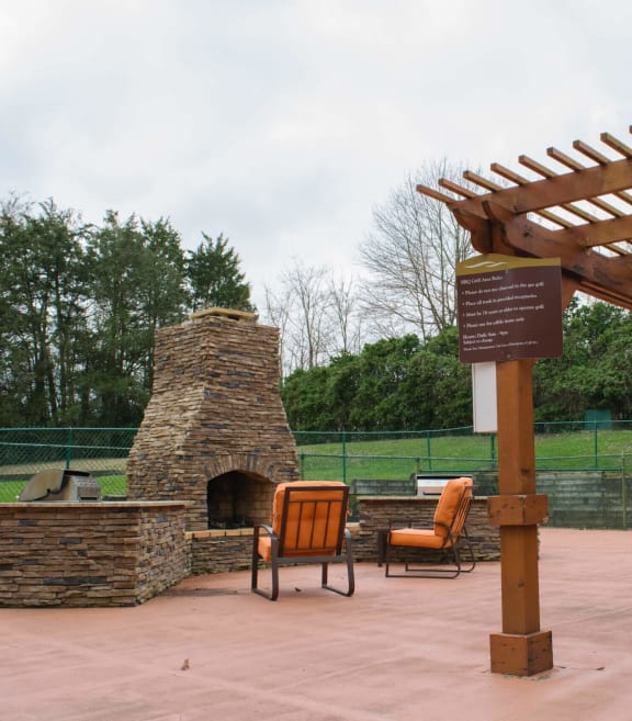 a picnic area with a stone fireplace and a wooden pergola