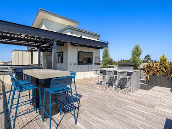 A modern outdoor dining area with blue chairs and a wooden table.