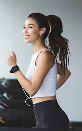 A woman is running on a treadmill in a gym.