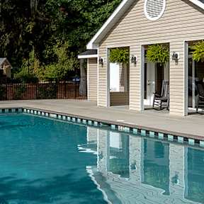 A pool area with a small building and trees in the background.