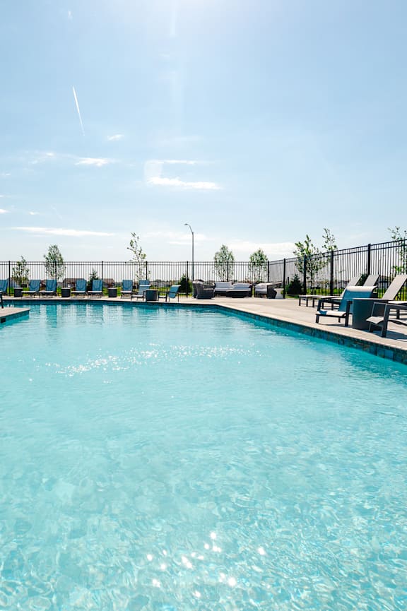 A large swimming pool with sun loungers and a building in the background. at Sagebrook Apartments, La Vista, Nebraska