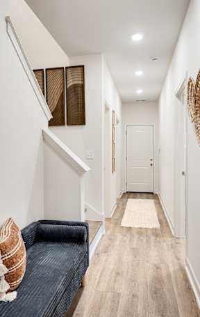 A hallway with a bench and baskets on the wall.