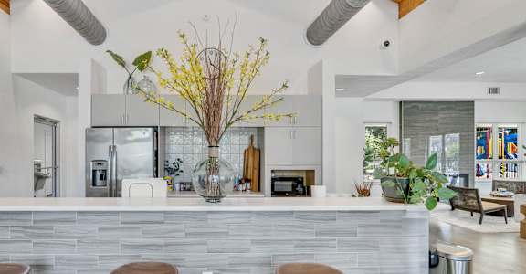 A modern kitchen with a stone counter and bar stools.