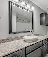 A bathroom with a sink, mirror, and toilet. at Cottonwood, Dallas, TX, 75240
