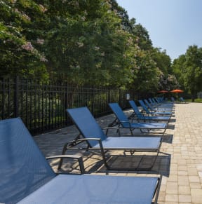 a row of blue lounge chairs next to a swimming pool