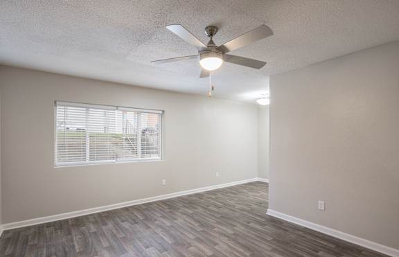 A room with a ceiling fan and a window with blinds.