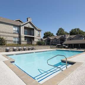 Sparkling swimming pool with lounge chairs and umbrellas at Hawthorne Apartment Homes.