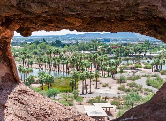 A view from inside a cave looking out onto a landscape with trees and buildings.