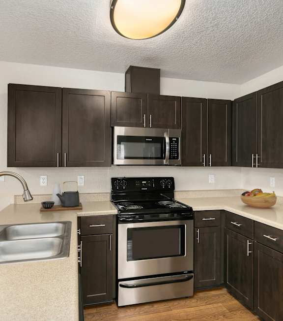 A kitchen with dark brown cabinets and stainless steel appliances.