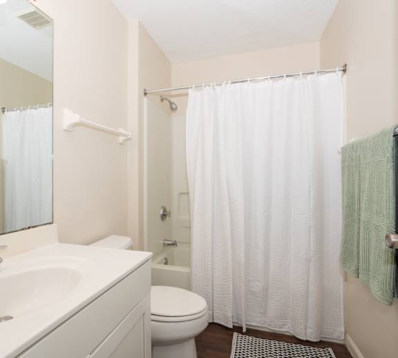 A white bathroom with a toilet, sink, and shower.