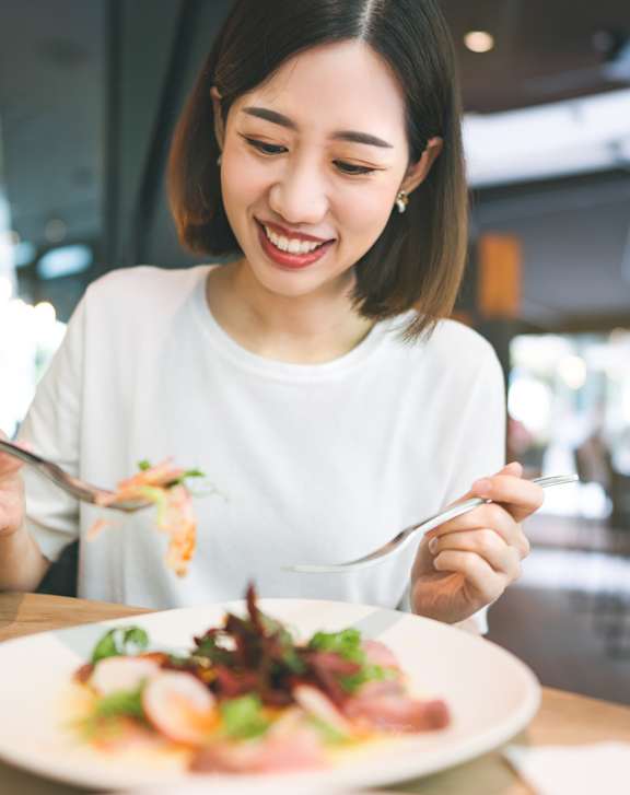 A woman is eating a salad at a restaurant.