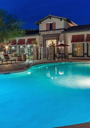 a swimming pool with chaise lounge chairs and umbrellas in front of a hotel
