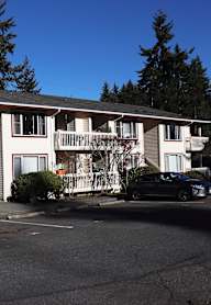 A black truck is parked in front of a two-story apartment building.