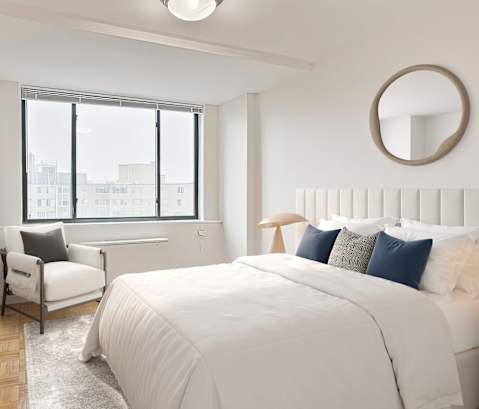 A bedroom with a large bed and a window overlooking the city.