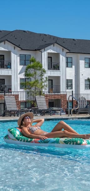 A woman is floating on a blue float in a pool.