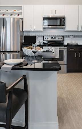 A modern kitchen with a black countertop and stainless steel appliances.