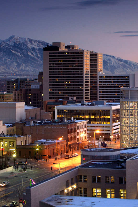 A cityscape at dusk with buildings and snow on the ground.