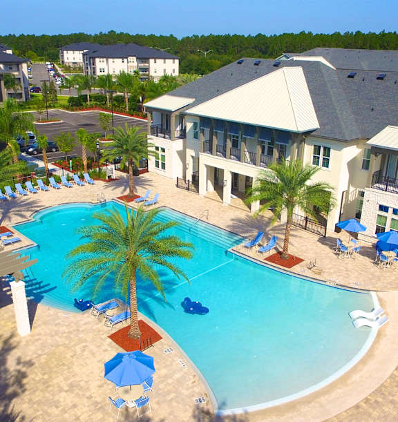 a large swimming pool with palm trees in front of a large apartment complex at Alaqua, Florida, 32258