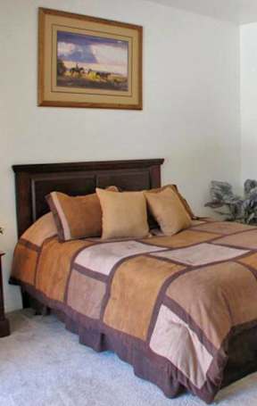 A bedroom with a bed, nightstand, and a painting on the wall.