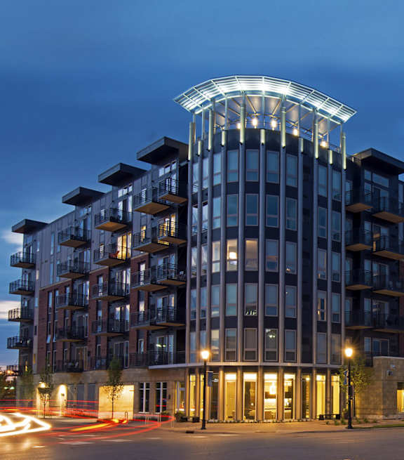 A modern building with a curved top is illuminated at night.