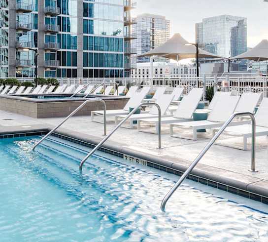 A swimming pool with lounge chairs and a view of a city skyline.