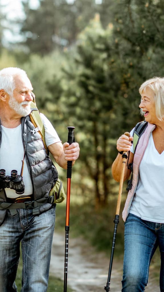 an older couple hiking through the woods with trekking poles at Amity Oak in Amityville, NY 11701