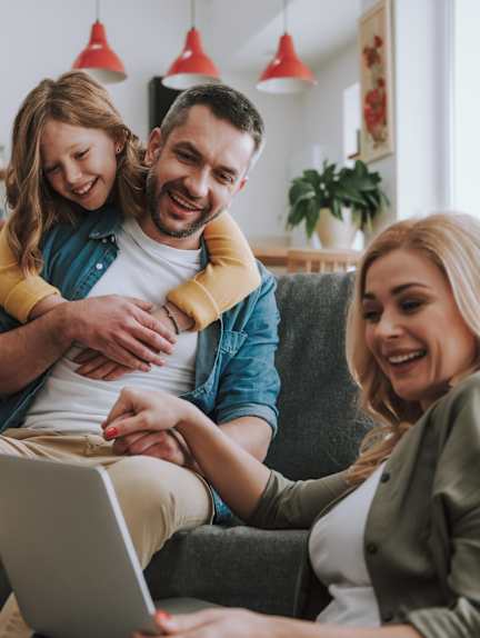 A family of three is sitting on a couch with a laptop at The Laurent at Laurel Apartments, Edmonton, AB, T6T 2T5