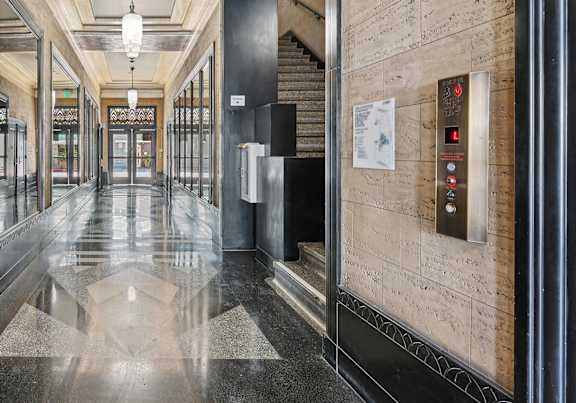 A hallway with a green door and a black and white floor.