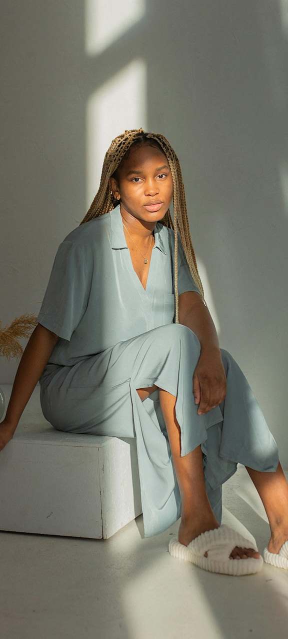 a woman sitting on a box wearing a blue dress and white shoes