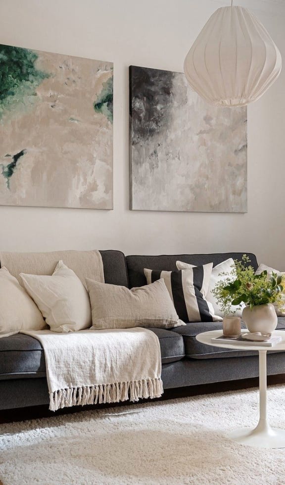 A living room with a couch and two paintings on the wall.