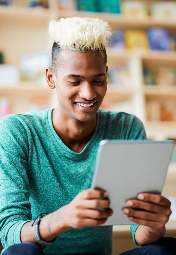 this is a photo of a young man browsing a tablet at the local bookstore.