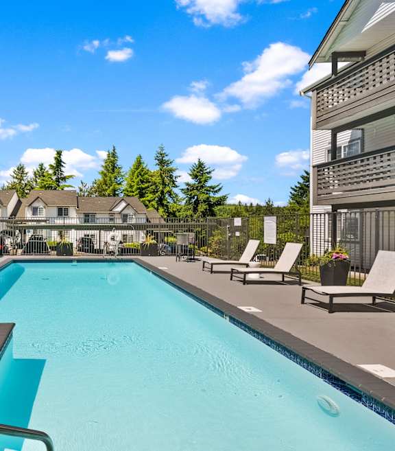 A large swimming pool with a slide and sun loungers.